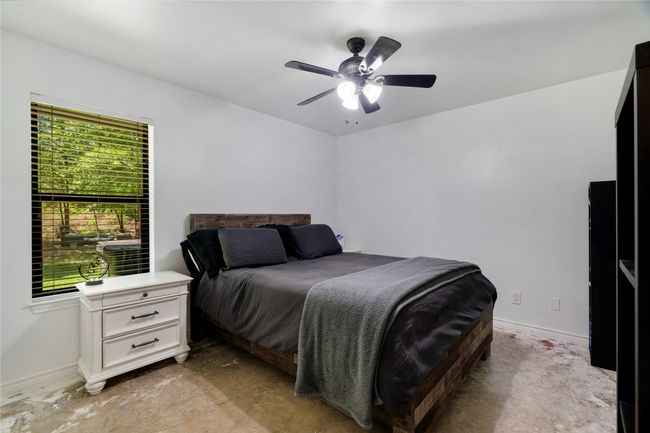 Bedroom featuring unfinished concrete flooring, baseboards, and ceiling fan | Image 14