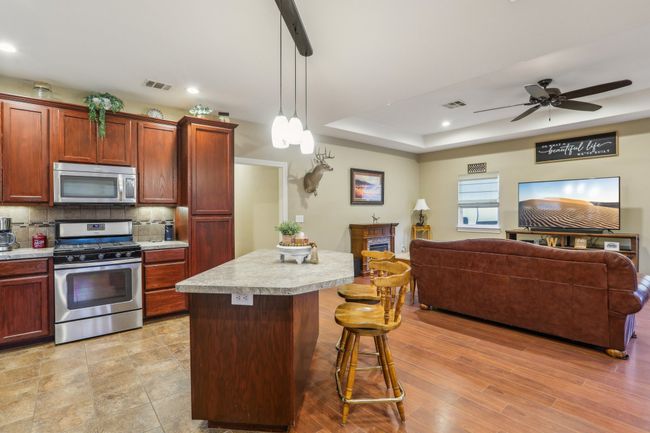 Kitchen featuring a kitchen island, a kitchen breakfast bar, decorative backsplash, hanging light fixtures, and stainless steel appliances | Image 15