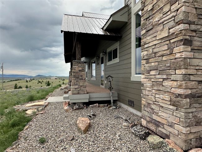 View of side of home with crawl space, a metal roof, and stone siding | Image 31