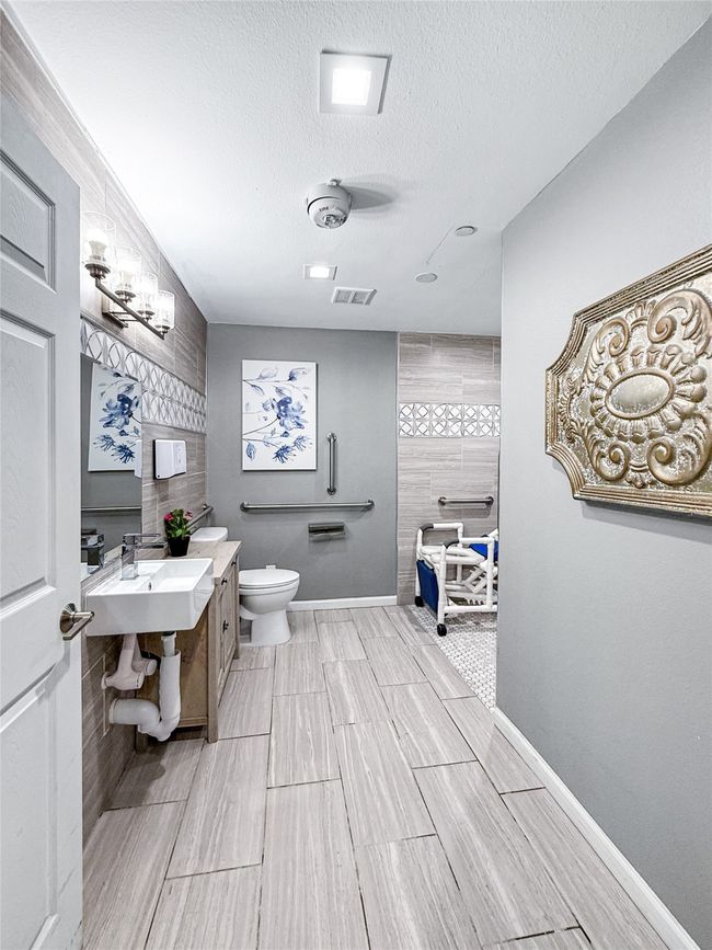 Bathroom featuring a textured ceiling, a walk in shower, wood tiled floors, and vanity | Image 22
