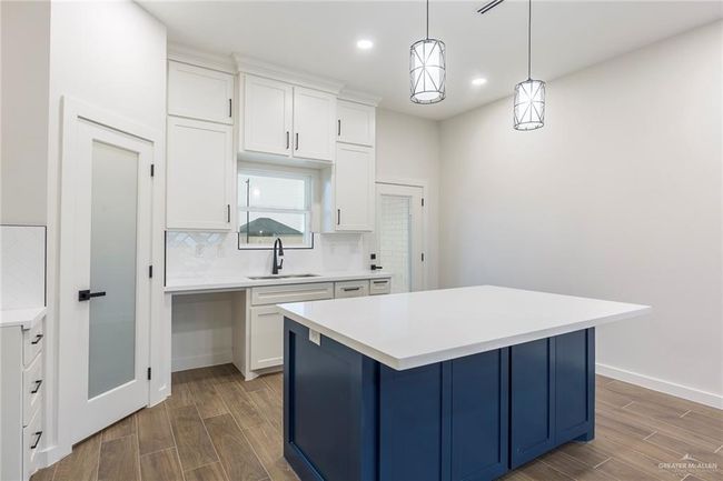 Kitchen with sink, white cabinetry, tasteful backsplash, hanging light fixtures, and a kitchen island | Image 14