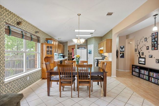 Dining area with wallpapered walls, light tile patterned floors, and a chandelier | Image 8