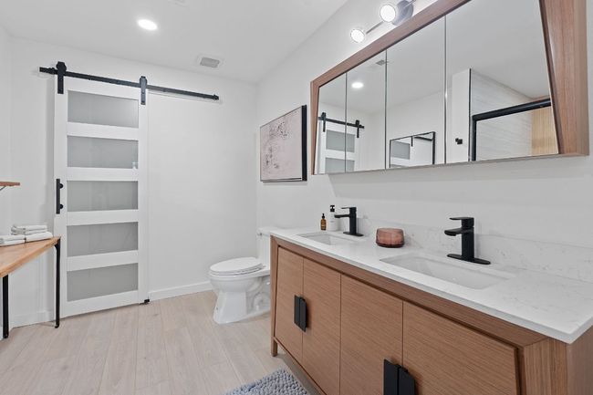 Bathroom featuring double vanity, wood finished floors, and a shower | Image 22