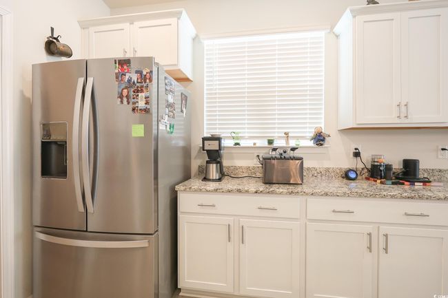 Kitchen with light stone counters, stainless steel fridge, and white cabinets | Image 7