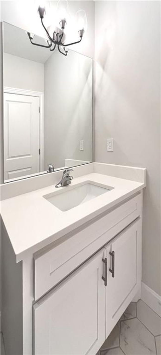 Bathroom with a chandelier, vanity, and marble look tiles | Image 45