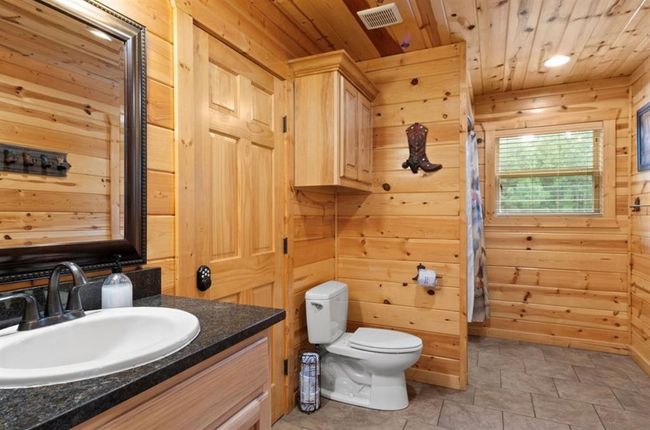Bathroom with wooden walls, wooden ceiling, vanity, and toilet | Image 29