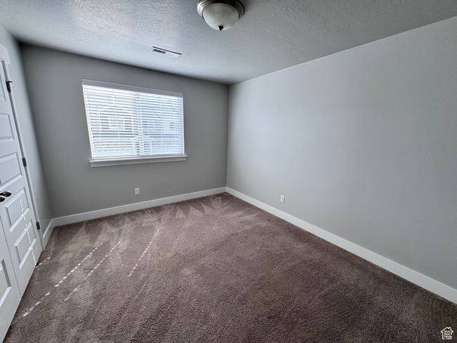 Carpeted empty room featuring baseboards, visible vents, and a textured ceiling | Image 23