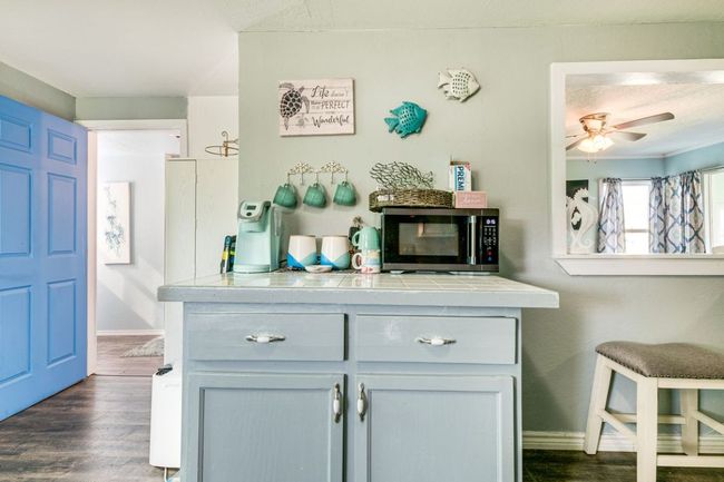 Bar with stainless steel microwave, a ceiling fan, dark wood-type flooring, and baseboards | Image 9