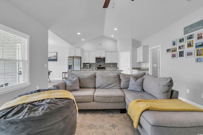 Living area featuring high vaulted ceiling, baseboards, a ceiling fan, and recessed lighting | Image 17