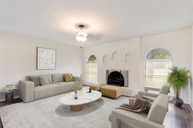 Living area featuring a fireplace with raised hearth, healthy amount of natural light, wood finished floors, a ceiling fan, and a textured ceiling | Image 5