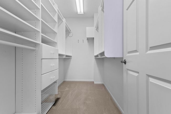Primary en suite has large walk-in closet with closet organizers that provide ample wardrobe space. | Image 13