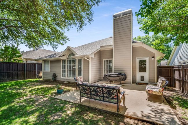 Rear view of property featuring a patio area, a chimney, roof with shingles, and an outdoor living space | Image 35