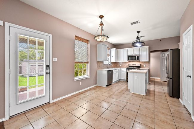 Kitchen featuring appliances with stainless steel finishes, healthy amount of natural light, light countertops, and decorative backsplash | Image 11