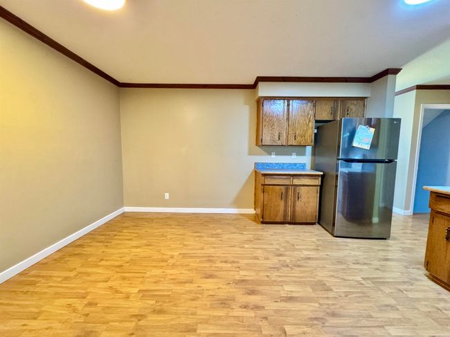 Kitchen featuring freestanding refrigerator, crown molding, light wood-type flooring, and light countertops | Image 7