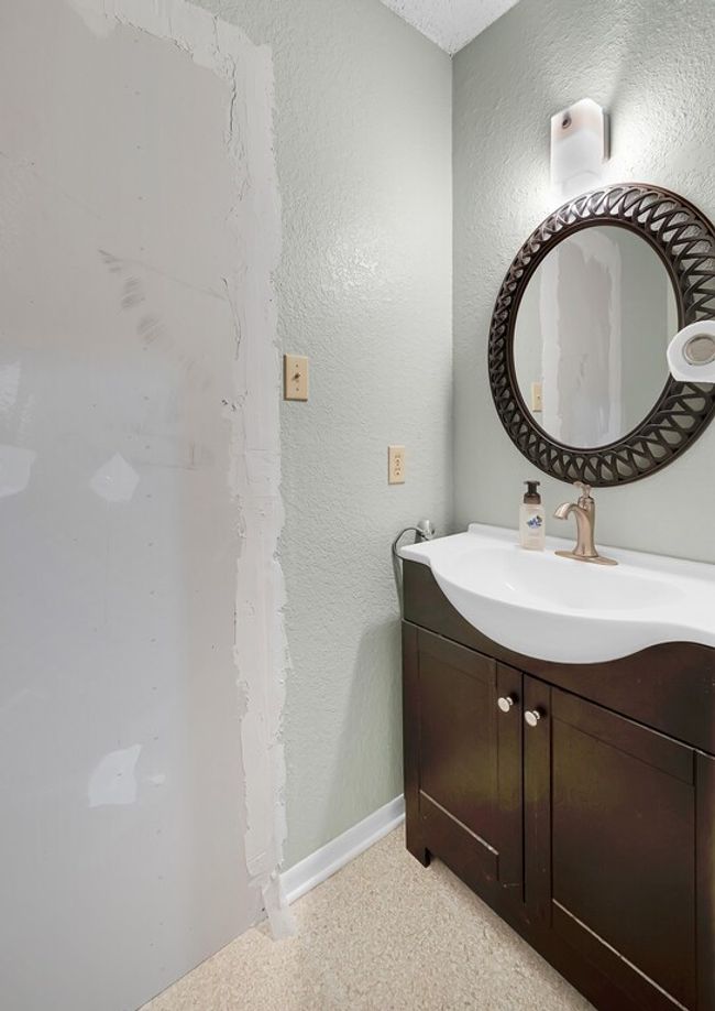 Bathroom with vanity, baseboards, and a textured wall | Image 17