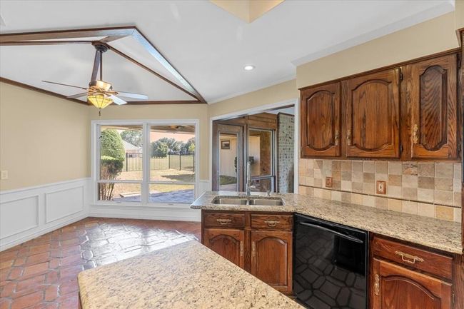 Kitchen with tasteful backsplash, ceiling fan, sink, black dishwasher, and vaulted ceiling | Image 9