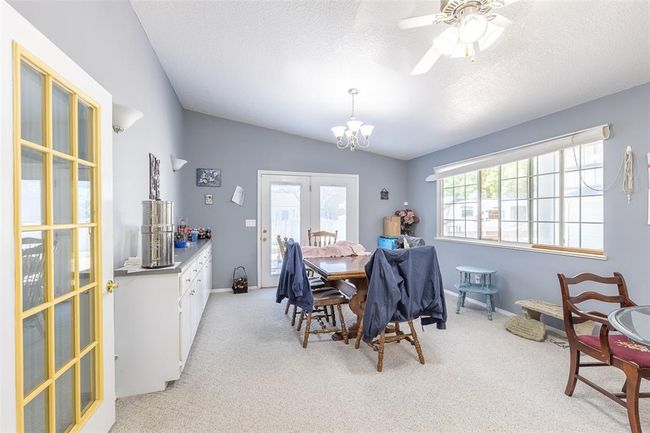 Dining space featuring light carpet, a chandelier, a ceiling fan, a textured ceiling, and baseboards | Image 29