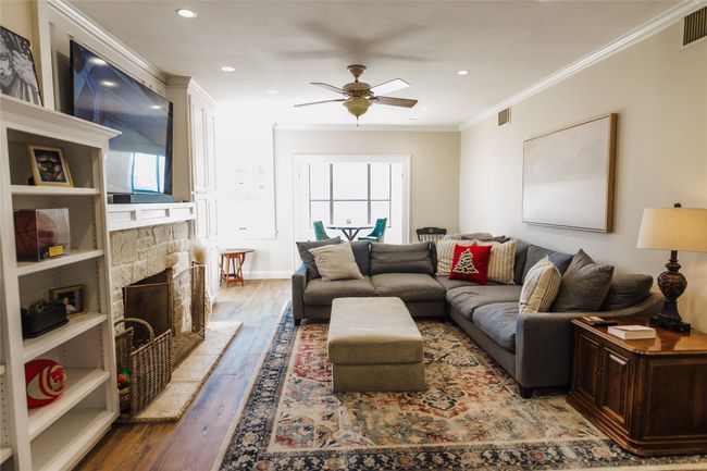 Living room featuring ceiling fan, wood-type flooring, crown molding, and a stone fireplace | Image 11