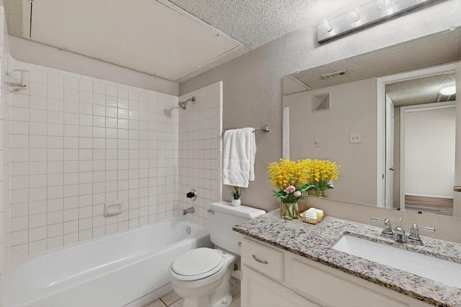Full bathroom with a textured ceiling, a textured wall, vanity, and shower / bathtub combination | Image 27