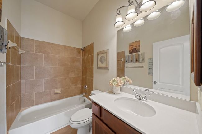This bathroom features a clean and modern design with a tiled shower-tub combo, a sleek vanity with a large mirror, and stylish lighting fixtures. The neutral color palette creates a welcoming atmosphere. | Image 31