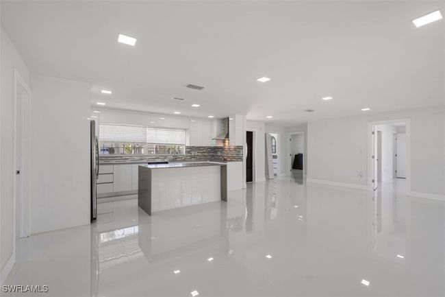 Kitchen featuring freestanding refrigerator, decorative backsplash, white cabinets, wall chimney exhaust hood, and modern cabinets | Image 5