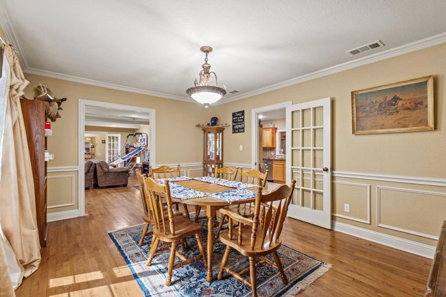 Dining room with light wood-type flooring, visible vents, crown molding, and a decorative wall | Image 13