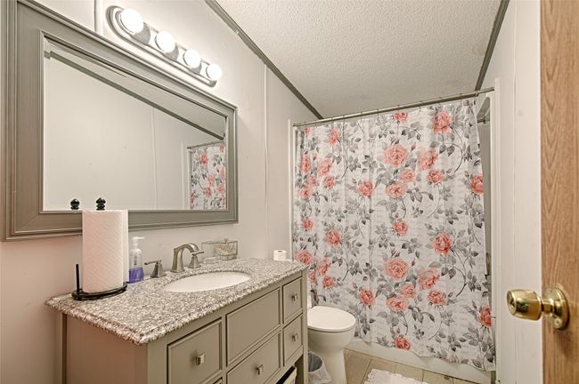 Bathroom with a textured ceiling, vanity, light tile patterned flooring, curtained shower, and ornamental molding | Image 20
