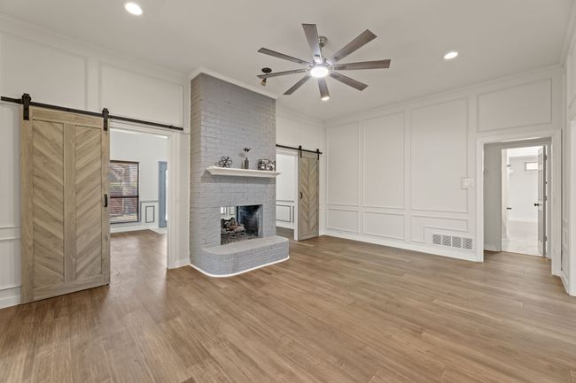 Unfurnished living room with a decorative wall, visible vents, ornamental molding, a ceiling fan, and a barn door | Image 13