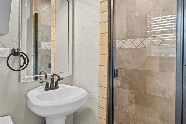 Bathroom with a sink, a stall shower, and a textured wall | Image 17