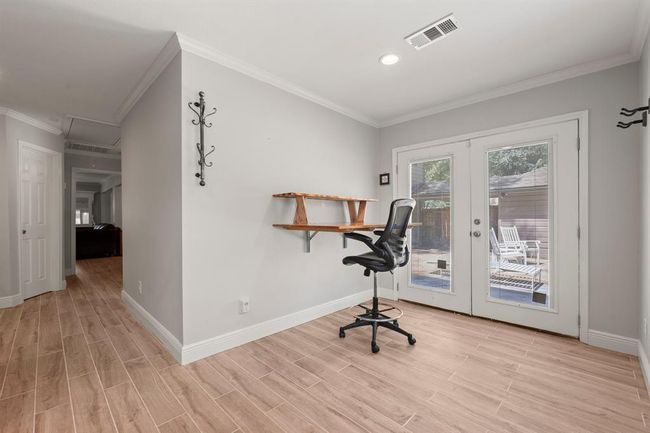 Bright, spacious bedroom featuring a wall-mounted desk. Double glass doors open to a patio area, offering natural light and outdoor views. | Image 22