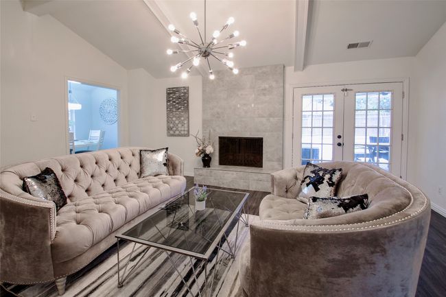 Living area featuring wood finished floors, a chandelier, a fireplace, and french doors | Image 9