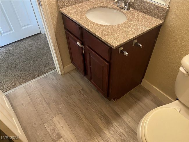 Half bath with baseboards, toilet, wood finished floors, a textured wall, and vanity | Image 17