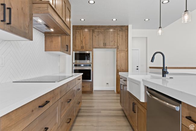 Kitchen featuring premium range hood, a sink, appliances with stainless steel finishes, and brown cabinetry | Image 8