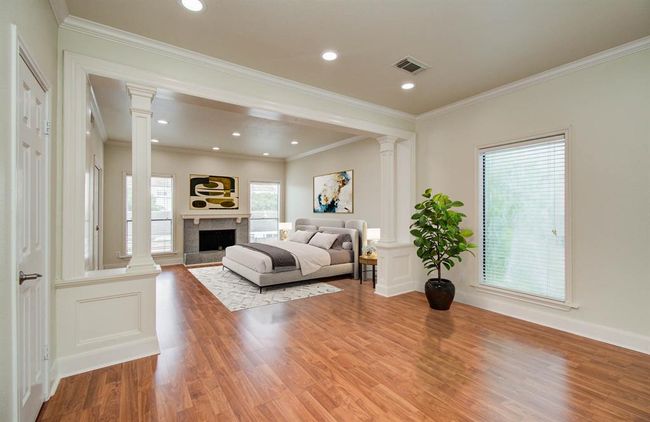 Virtually staged spacious primary bedroom with a cozy fireplace and versatile open area, perfect for an office. | Image 4