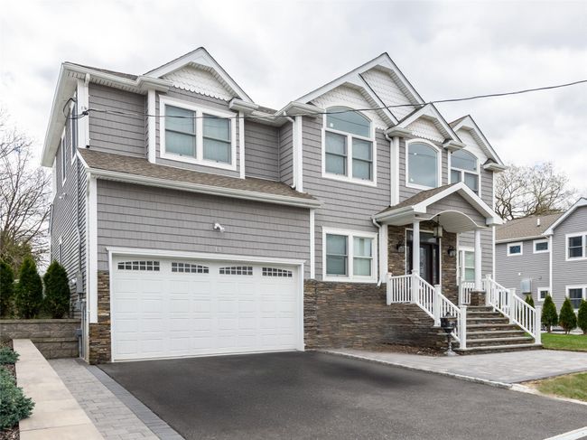 View of front of home with driveway, stone siding, a shingled roof, and a garage | Image 26