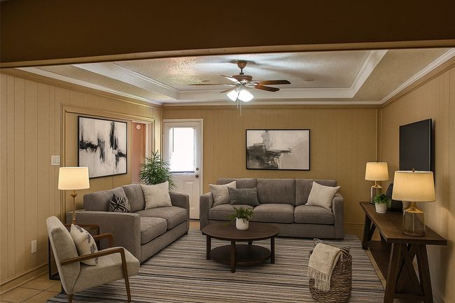 Living room with a tray ceiling, crown molding, a ceiling fan, and a textured ceiling | Image 4