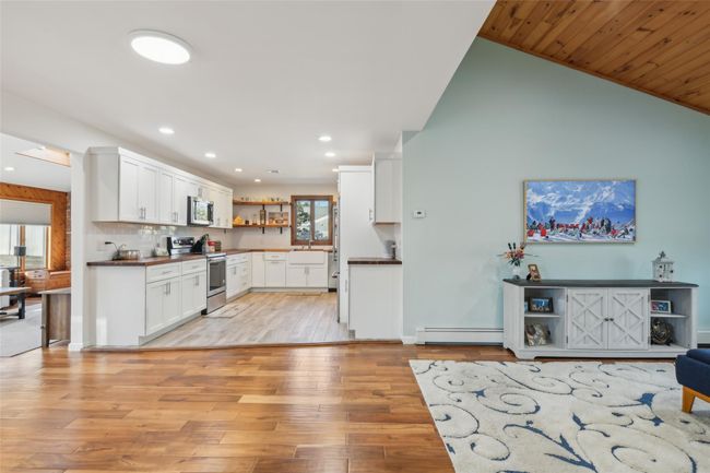 Kitchen with open shelves, appliances with stainless steel finishes, dark countertops, light wood-type flooring, and baseboard heating | Image 10