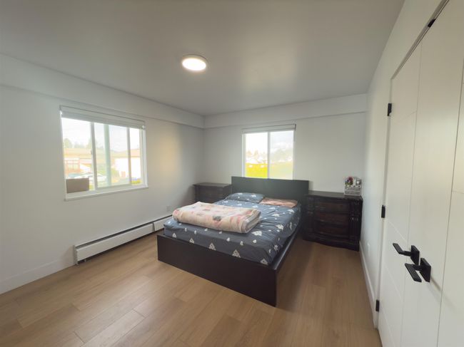 Bedroom with multiple windows, baseboard heating, and wood finished floors | Image 11