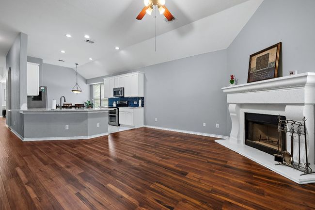 Kitchen featuring stainless steel appliances, lofted ceiling, open floor plan, ceiling fan, and a sink | Image 13