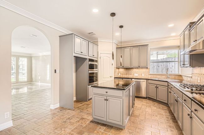 Kitchen featuring arched walkways, a sink, stone tile floors, stainless steel appliances, and gray cabinets | Image 15