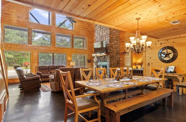 Dining space with wooden ceiling, wooden walls, high vaulted ceiling, a fireplace, and finished concrete flooring | Image 13