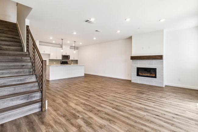 Unfurnished living room with recessed lighting, baseboards, wood finished floors, stairway, and a tile fireplace | Image 6