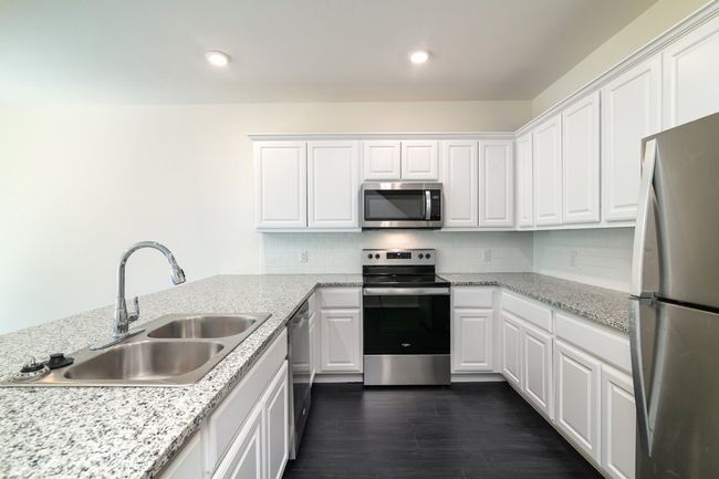 Kitchen featuring white cabinetry and appliances with stainless steel finishes | Image 7