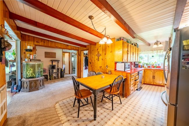 Dining space featuring light colored carpet, wooden walls, and a chandelier | Image 4