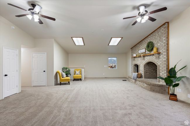 Interior space featuring a fireplace, a ceiling fan, and vaulted ceiling | Image 11