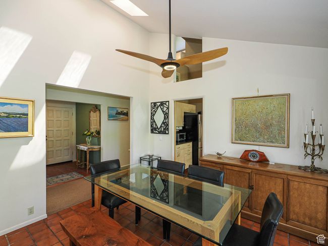 Dining space with a skylight, high vaulted ceiling, tile patterned flooring, and ceiling fan | Image 16
