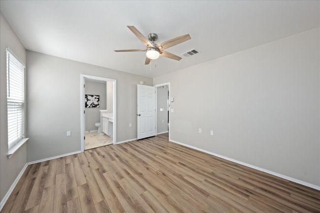 Unfurnished bedroom with a ceiling fan, baseboards, visible vents, light wood-style flooring, and ensuite bathroom | Image 18