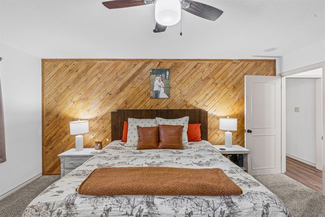 Bedroom featuring wood walls, carpet floors, and a ceiling fan | Image 17