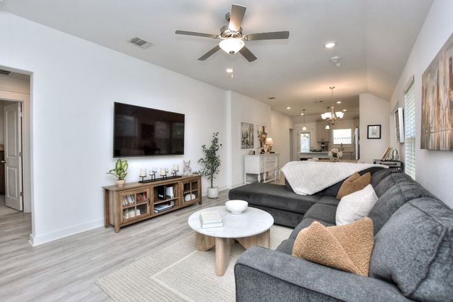 Living room with ceiling fan with notable chandelier, light wood-type flooring, visible vents, recessed lighting, and baseboards | Image 9