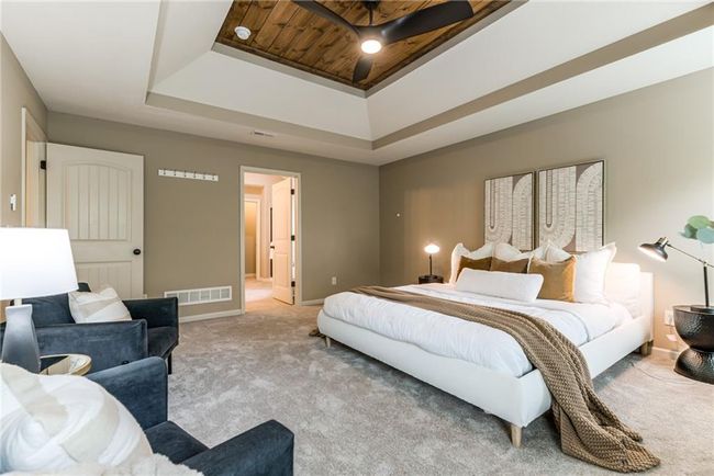 Bedroom featuring a tray ceiling, light colored carpet, and ensuite bath | Image 24
